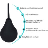 The Shibari Triton Easy Squeeze Enema Bulb features a black bulb syringe with a narrow nozzle and offers five highlighted benefits: 1. Soft and comfortable non-toxic medical-grade PVC, 2. Leak-proof design, 3. Maintains shape with repetitive squeezing, 4. Ergonomic design with a non-slip grasp, 5. Easy to clean and use with its flexible tip.
